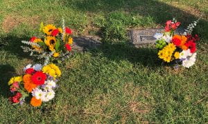 3 bouquets of flowers at a gravesite