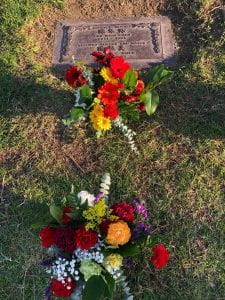 Two flower bouquets in front of a grave marker