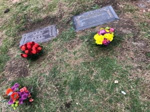 three bunches of flowers in front of two grave markers