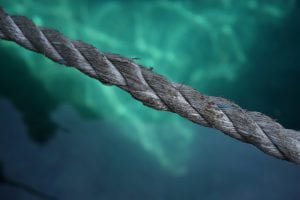 Taut grey rope with green water in the background