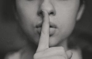 Photograph of a person holding their finger to their lips