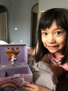 Photo of a girl smiling next to a unicorn jewelry box
