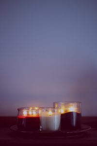 photograph of three lit candles with a twilight sky in the background