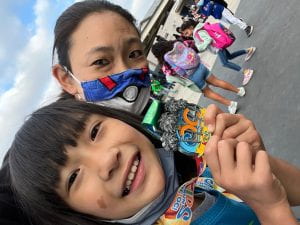 Photograph of the author wearing a Pokemon mask and a multiracial little girl holding a running medal