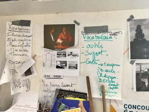 Picture of a wall in an art classroom in France. On the wall is taped vocabulary and pictures.