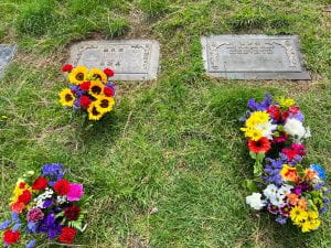 Picture of two grave markers and four bunches of flower 
