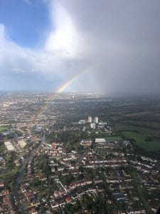 A photograph of a rainbow taken from an airplane over a city