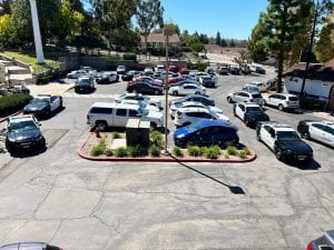 Photograph of a parking lot, with seven police car lined up around the perimeter of the lot