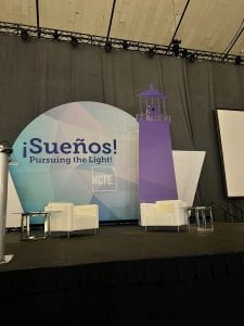 Photograph of a stage with a lighthouse and a circle with the words ¡Sueños! Pursuing the Light and the National Council of Teachers of English logo