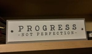 Photograph of a sign that reads Progress Not Perfection