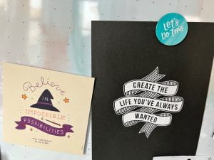 A picture of two cards side by side, one that says "Believe in Impossible Possibilities" (Eva Evergreen, Julie Abe) and another that says "Create the Life You've Always Wanted" held up by a magnet that says, "Let's Do This"