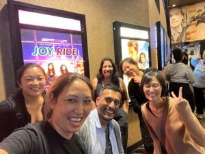 Photo of Asian American people in front of Joy Ride movie poster
