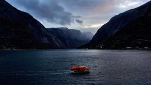 Photo of a boat on water in the evening with dark clouds around it