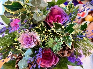 A bouquet of flowers including bright blossoms of kale and pine